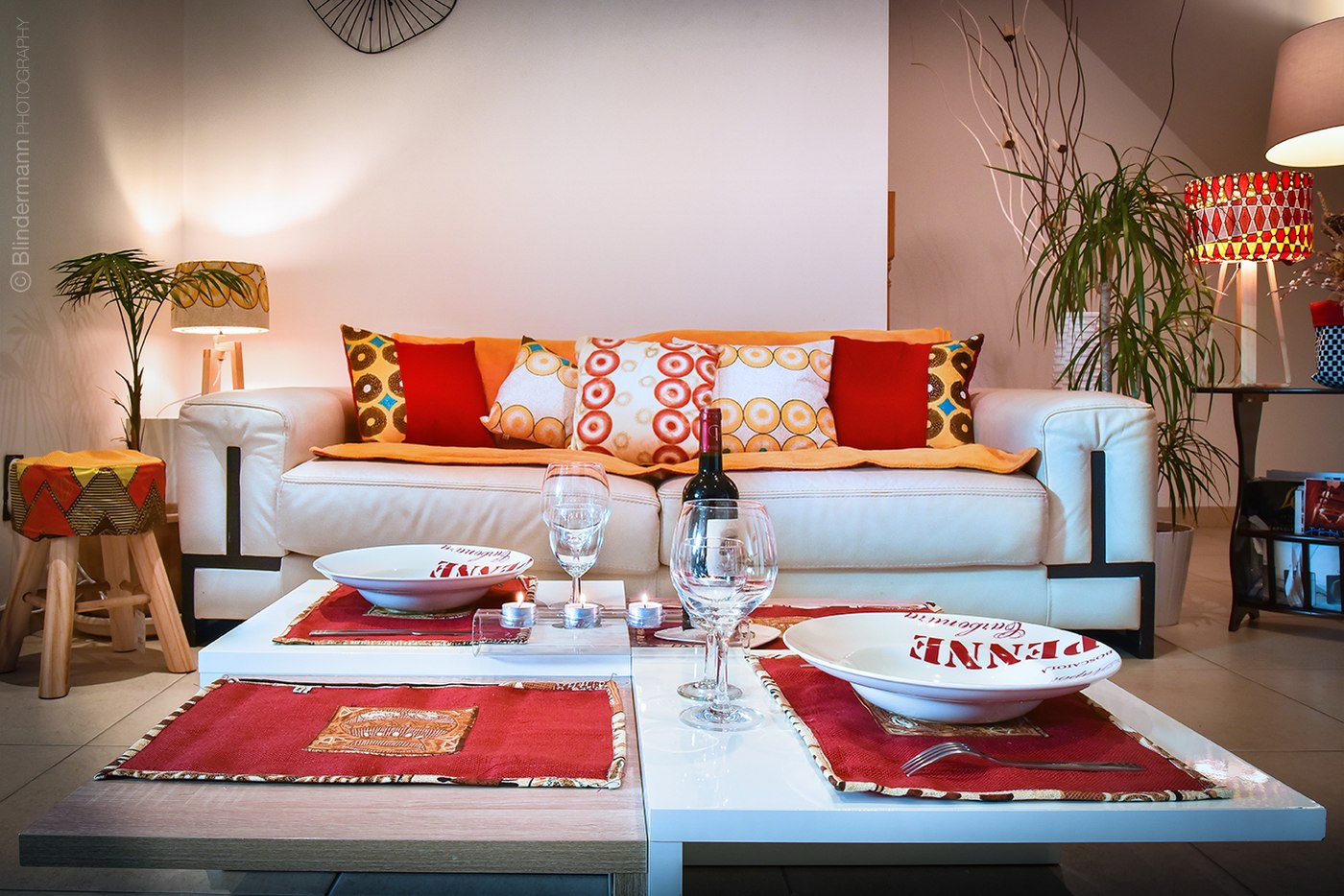 Salon clair avec canapé et coussins aux motifs colorés.