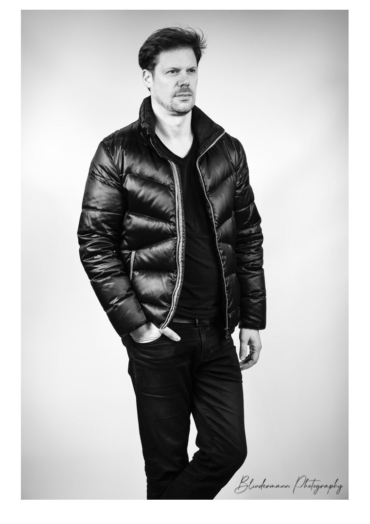Portrait en noir et blanc d’un homme portant une veste matelassée.